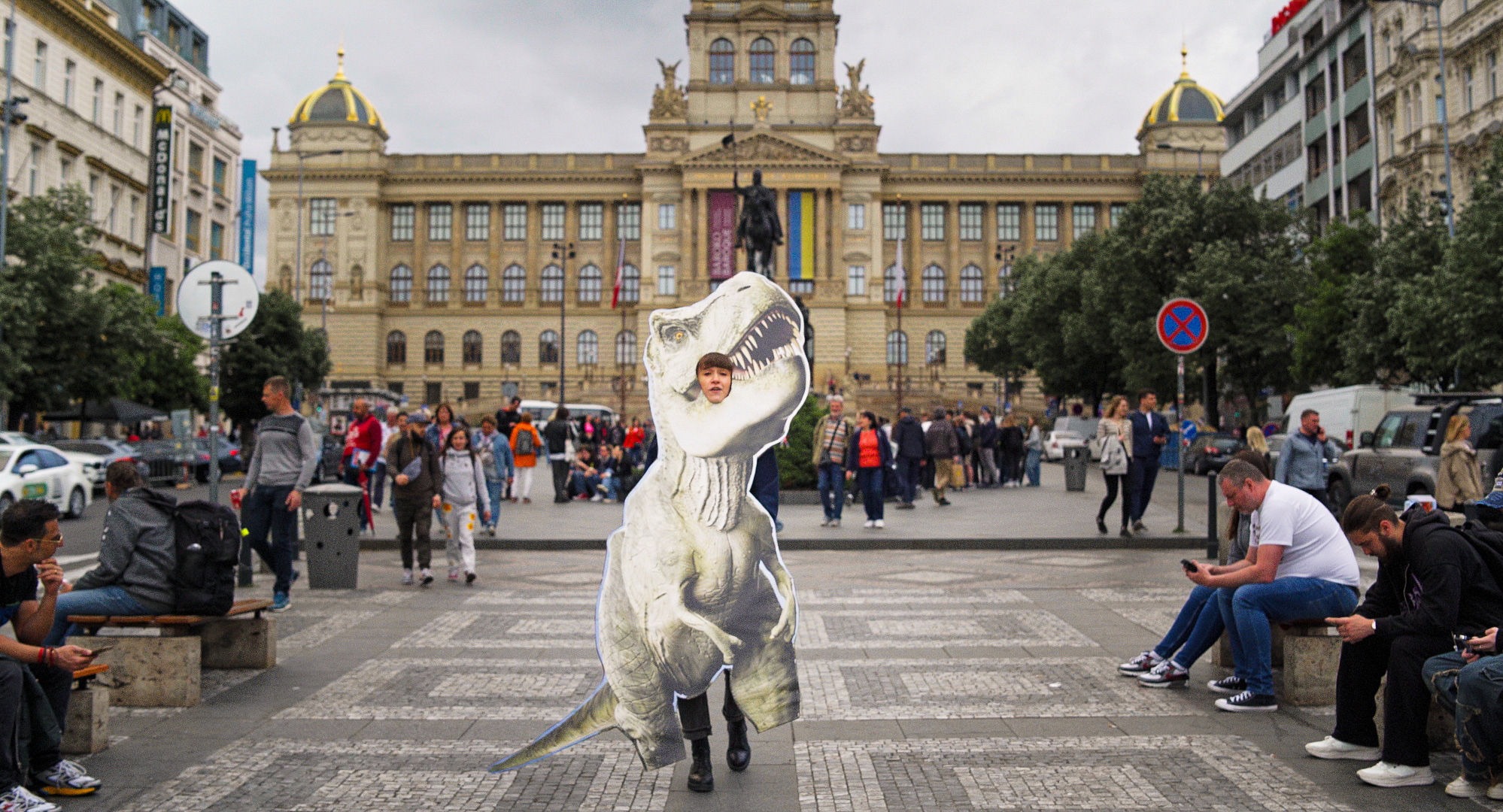 Žena kráčí po Václavském náměstí v kostýmu dinosaura.