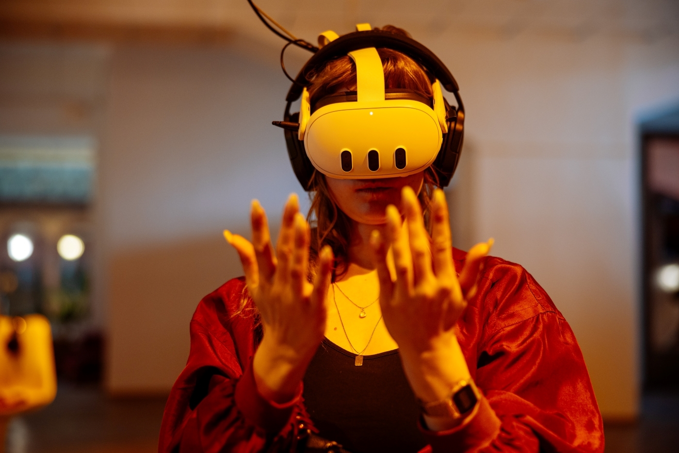 Žena s VR brýlemi a sluchátky si prohlíží ruce ve virtuální realitě.